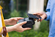 © sofiko14 - A person using a smartphone to make a contactless payment at a point-of-sale terminal. Modern technology and finance concept.