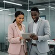 © Taposh - Two smiling business professionals looking at a tablet together in an office
