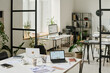 © TrueFrame Collective - No people wide interior shot of modern office with laptops, computers and documents on desks, copy space