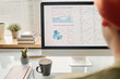 © TrueFrame Collective - Selective focus shot of unrecognizable man looking at desktop computer monitor with graphs and charts on screen