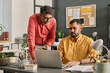 © TrueFrame Collective - Two mature and young Indian managers wearing smart casual clothes looking at laptop screen discussing work