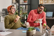 © TrueFrame Collective - Two cheerful Indian men wearing casual clothes spending lunch break in office laughing at funny story