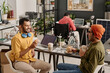 © TrueFrame Collective - Two joyful Indian male coworkers chatting while having lunch at work in modern office