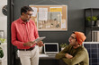 © TrueFrame Collective - Mature and young Indian coworkers discussing business project at work in modern office, copy space