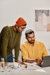 © TrueFrame Collective - Vertical shot of two young Indian men wearing casual clothes working together on new business strategy