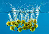 Gooseberrys in water with splash, blue background