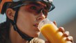 © Ayesh Creatives - Woman cyclist drinking orange juice refreshment after biking workout for fitness and health outdoors activity