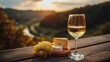 © backup_studio - A glass of white wine with cheese and grapes on a wooden table outdoors with a mountain landscape at sunset. Dinner.