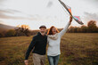 © Halfpoint - Senior couple flying a kite during warm autumn evening.