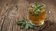 © The 2R Artificiality - Rustic wooden table featuring glass cup filled with sage herbal tea surrounded by fresh and dried leaves, highlighting homeopathic health benefits