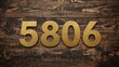 © AkuAku - Vintage-style wooden digits 5806 coated in gold against a patterned plank backdrop