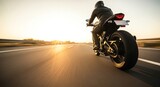 Motorcyclist riding on highway during sunset