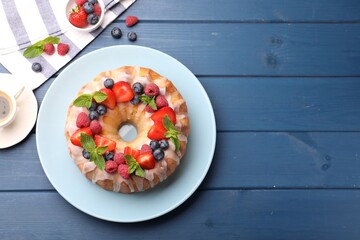 Wall Mural - delicious bundt cake with berries, glaze and mint on blue wooden table, flat lay. space for text