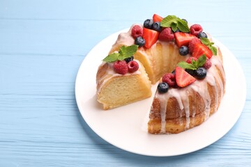 Wall Mural - pieces of delicious bundt cake with berries, glaze and mint on light blue wooden table, closeup
