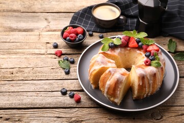 Wall Mural - pieces of delicious bundt cake with berries, glaze and mint on wooden table, closeup