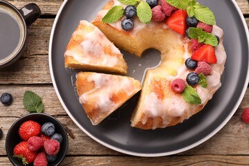 Wall Mural - pieces of delicious bundt cake with berries, glaze and mint on wooden table, flat lay