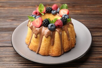 Wall Mural - tasty bundt cake with berries, chocolate and mint on wooden table, closeup