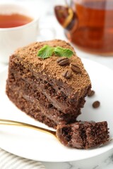 Wall Mural - piece of delicious chocolate cake with coffee beans, mint and fork on table, closeup