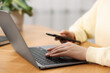 © New Africa - Copywriter using laptop at wooden table indoors, closeup