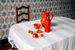 © Maria Sher/Stocksy - Bright Red Pottery and Fresh Produce on Striped Tablecloth