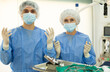© JackF - Confident professional veterinarians, young man and senior woman, wearing sterile outfit and gloves standing by operating table, ready to conduct surgical operation to sick pet at veterinary clinic