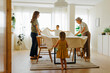 © BONNINSTUDIO/Stocksy - Family putting tablecloth on dining table at home
