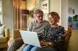© Marko Geber - Happy senior couple using laptop together at home on the couch