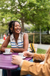 © Alvaro Lavin/Stocksy - Students laughing and drinking coffee at an outdoor table