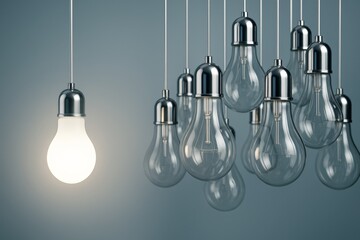 Wall Mural - one illuminated light bulb among many unlit bulbs hanging against a soft blue background symbolizing