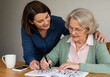 © jmdesigns608 - Woman helping senior with crossword puzzle, care concept