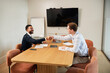 © Elena Kharichkina/Stocksy - Business meeting with handshake in modern office setting