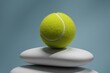 © Davide Illini/Stocksy - Tennis ball balanced on smooth stacked stones against blue background
