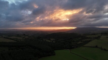 Wall Mural - Aerial view of a scenic morning sunrise breaking through the clouds over rural Wales, United Kingdom