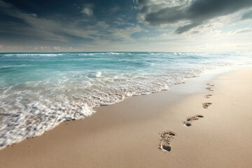 Wall Mural - Footprints on a tropical beach with gentle waves and a dramatic sky creating a serene atmosphere during sunset hours