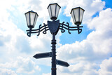 a vintage street lamp with with two directional signs pointing in opposite directions. navigation and direction around the city or globally.