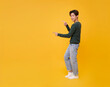 © NaMong Productions - Copy space choice concept cheerful Asian man presenting pointing finger on yellow background for ad banner, product mockup, decision making, and marketing design.