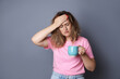 © New Africa - Woman with cup of coffee suffering from hangover on grey background