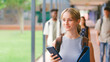 © Monkey Business - Female High School Or Secondary Student Looking At Social Media Or Internet On Phone Outdoors