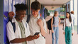 © Monkey Business - Two Male High School Or Secondary Students Looking At Social Media Or Internet On Phone By Lockers