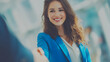 © plaksa - Professional businesswoman in blue blazer smiling and shaking hands with colleague, close-up shot, modern office background with soft natural lighting, confident and friendly expression, cinematic dep