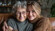 © Johannes - portrait of old grandma and adult granddaughter hugging with love on sofa while looking at camera happy young woman with eyeglasses hugging from behind older grandma with spectacles generation family