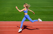 © Yevhen - Woman in sportswear jogging on stadium. Sportswoman in sportswear jumping. Woman running jump on stadium track. Fitness woman on stadium, run. Young fitness woman runner running on stadium track
