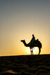 © cn0ra - Indian Man Riding Camel During Sunrise at Thar Desert in Rajasthan, India