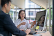 © Apichat - Businesswoman showing information on computer screen to businessman in office