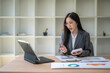 © Apichat - Businesswoman analyzing charts and holding calculator during video conference