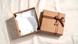 © Sojib_Islam - Open gift box mockup with brown satin ribbon bow and lid on white fabric background with tissue paper