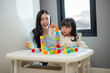 © geargodz - happy toddler girl playing wooden block toy cubes with her mother on table