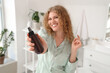 © Pixel-Shot - Beautiful young happy woman with hair spray in bathroom at home