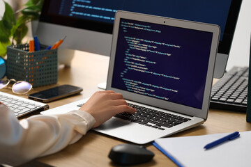 female programmer's hand working with laptop at table in office, closeup