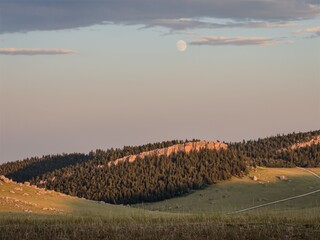 Wall Mural - moon rising over bighorn mountains with sunlit hills and rocks in wyoming